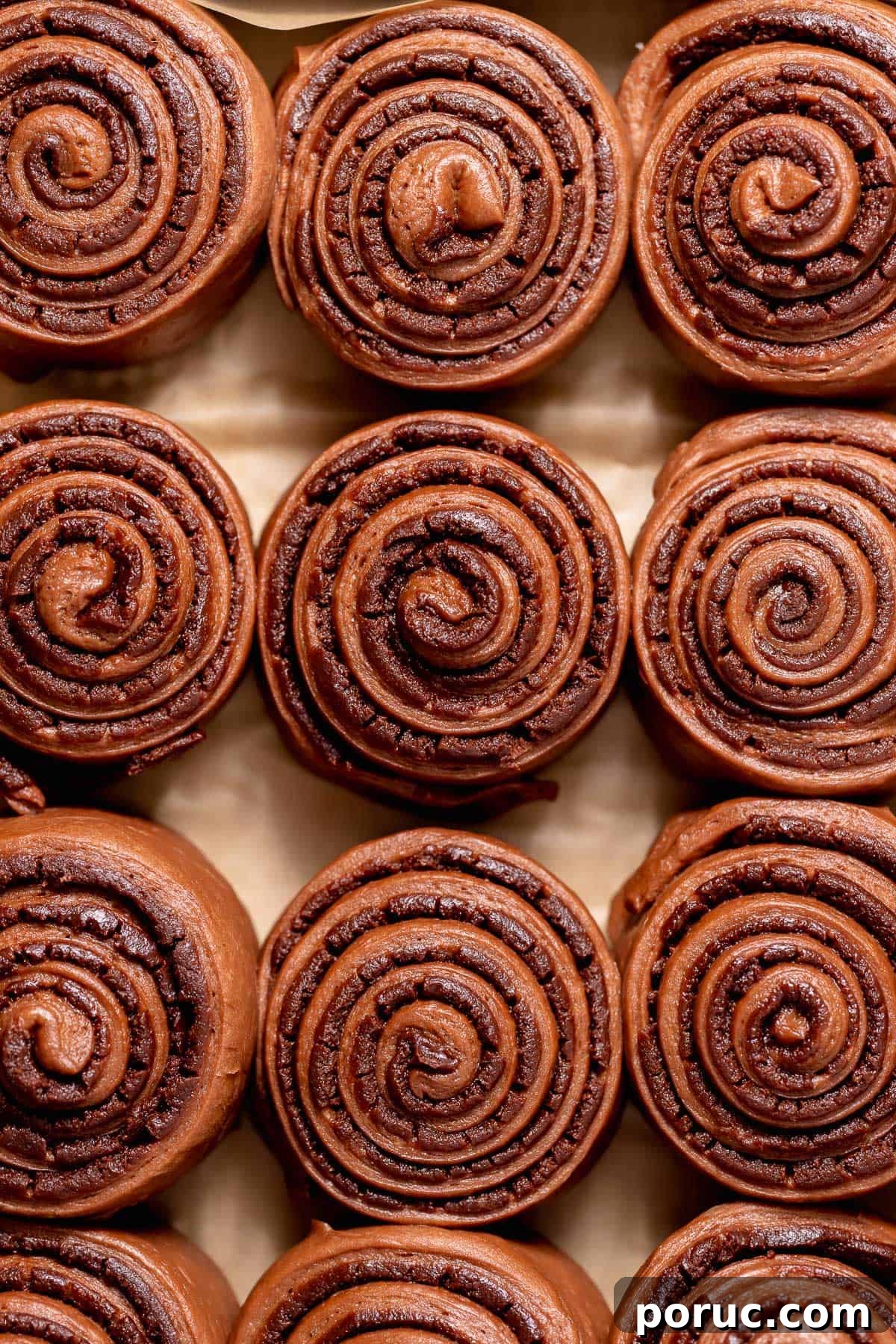 Chewy Cosmic Brownie Roll Recipe with Sprinkle Filling 8 Proofed chocolate brownie rolls in a parchment-lined baking pan, showing their soft, risen swirls before baking.