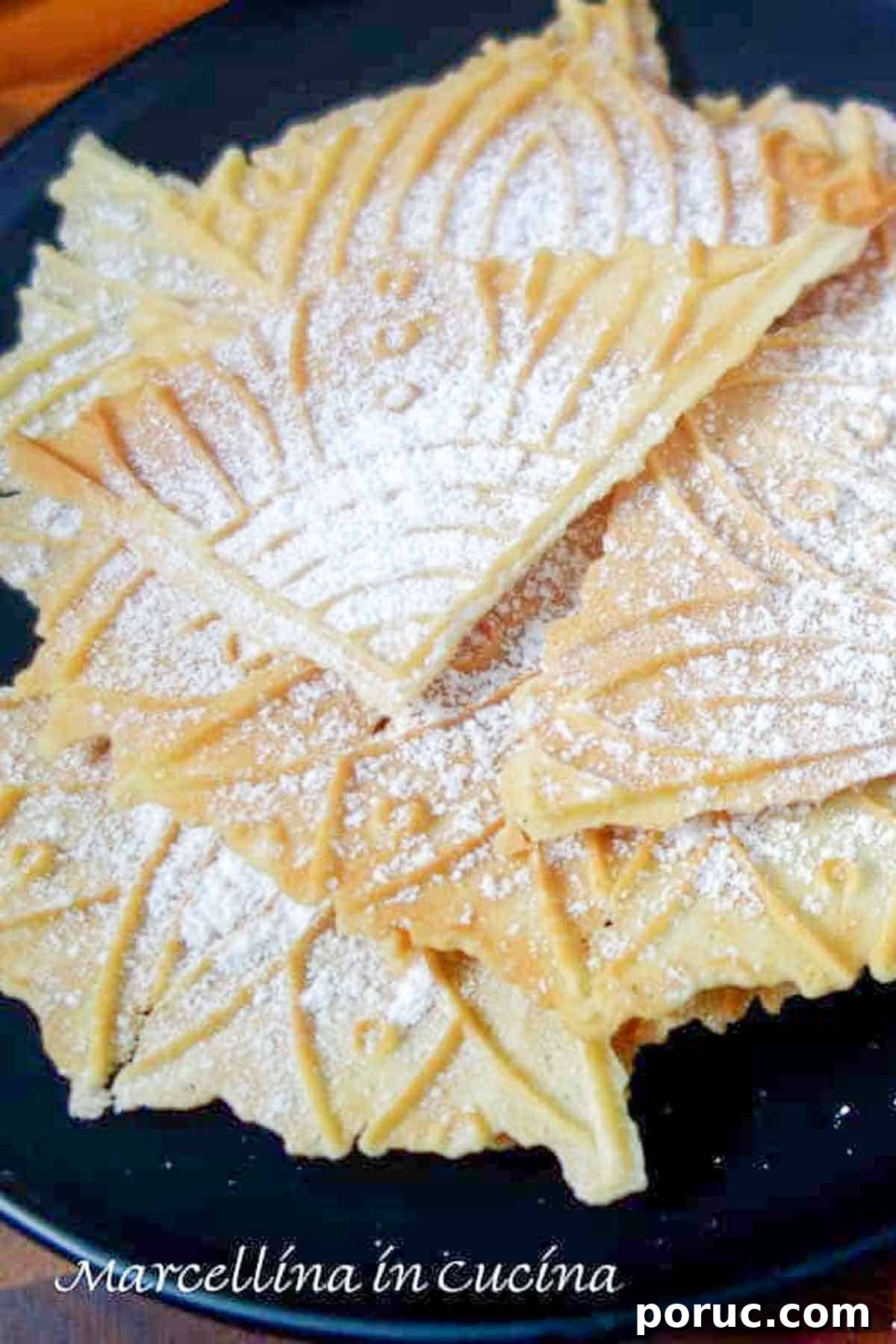 Crisp Lemon Pizzelle Cookies Recipe – Light Citrus Italian Wafers 2 Lemon pizzelle dusted with powdered sugar on a black plate.