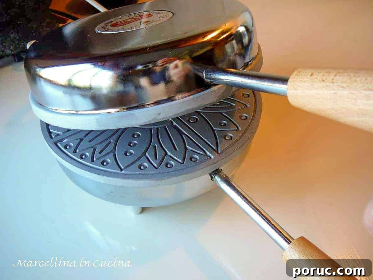 Crisp Lemon Pizzelle Cookies Recipe – Light Citrus Italian Wafers 4 a stainless steel pizzelle iron partially opened showing the griddle inside.