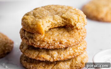 Elegant Lemon Sugar Cookies with Minimal Effort 11 Lemon sugar cookies stacked next to a bowl of lemons and sparkling sugar. A bite is missing from the top cookie showing the texture of the inside.