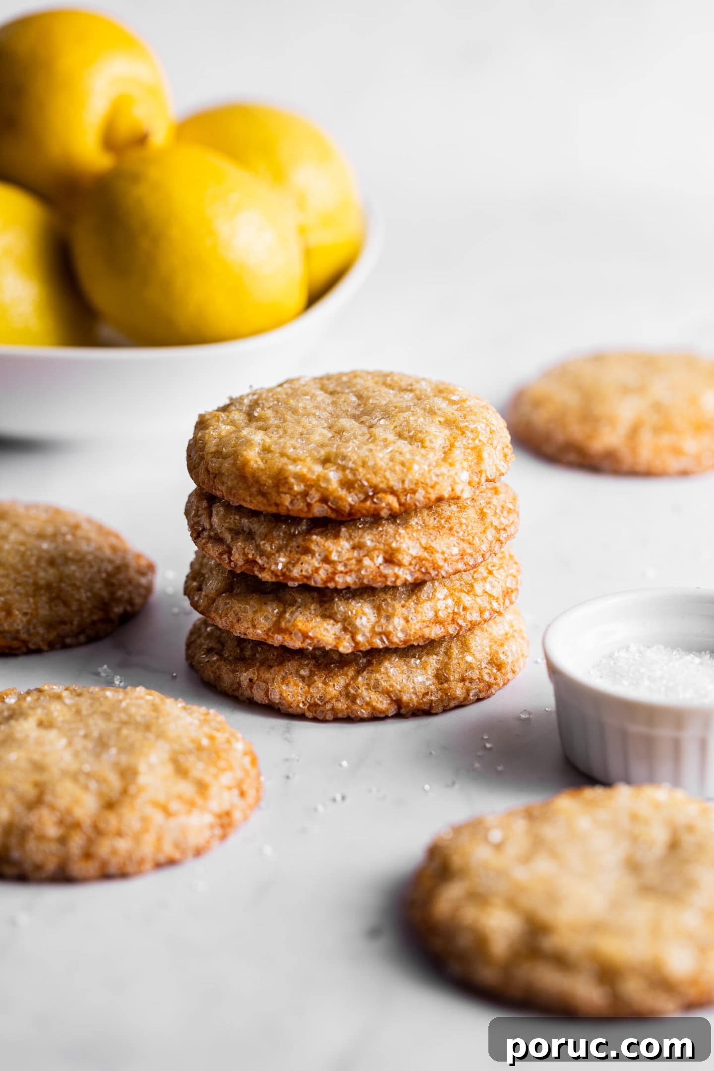 Elegant Lemon Sugar Cookies with Minimal Effort 3 Lemon sugar cookies stacked on top of each other next to a bowl of fresh lemons