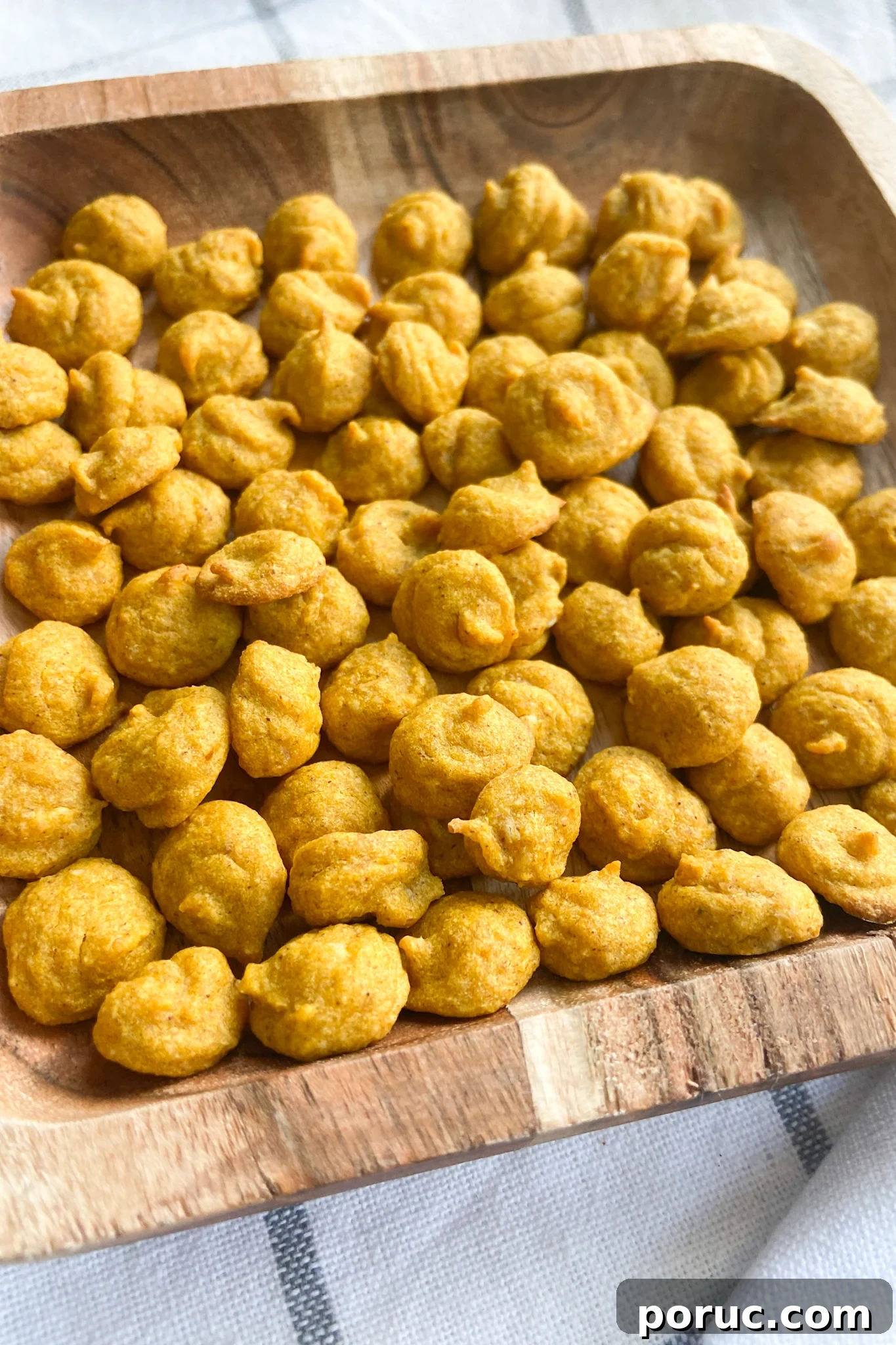 Homemade Pumpkin Baby Puffs: Soft Finger Food for Infants 2 Pumpkin puffs served on a wooden plate