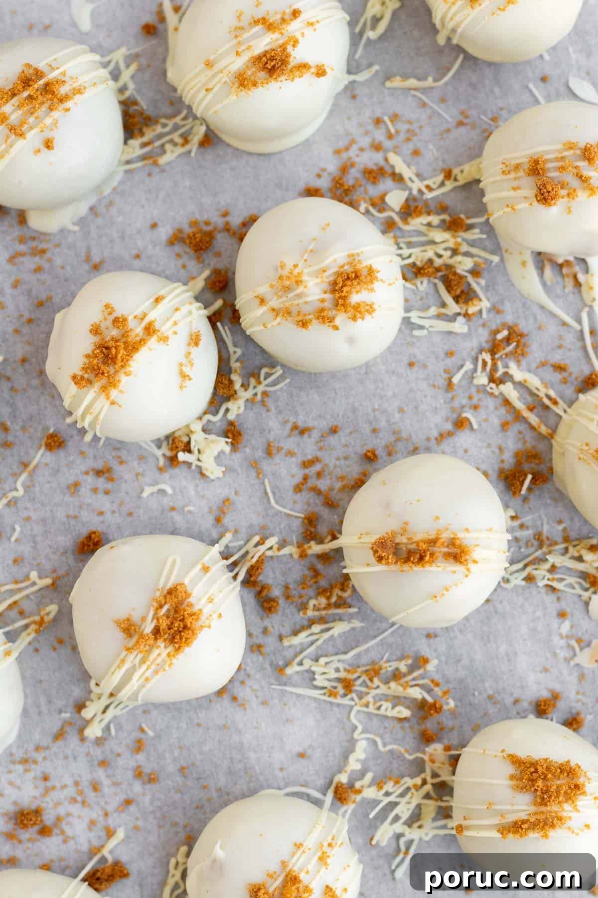 Decadent Biscoff Truffles Recipe: No-Bake Chocolate Treats 3 biscoff truffles covered in white chocolate and Biscoff crumbs on a parchment lined baking sheet