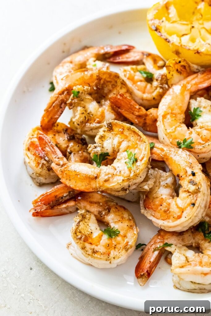 Blackstone Griddle Lemon Garlic Shrimp Recipe — Quick Grill Meal 2 Grilled shrimp topped with parsley, garlic and lemon juice on a white plate