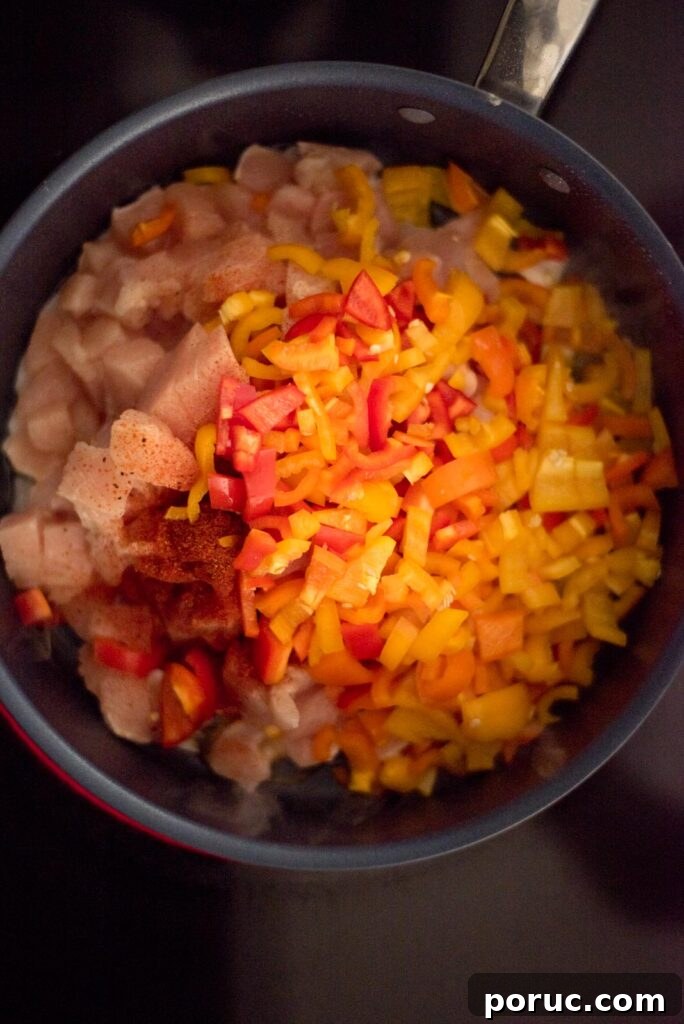 Southwest Chicken Skillet Recipe with Peppers and Black Beans 4 Chopped bell pepper, taco seasoning, and chicken in a skillet on the stove.