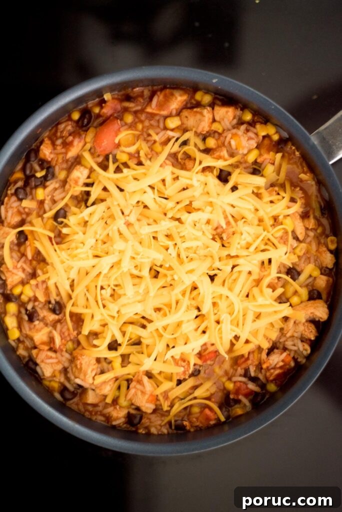 Southwest Chicken Skillet Recipe with Peppers and Black Beans 10 Cheese added to the skillet for southwest chicken and rice skillet.