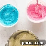 Whipped Cotton Candy Cake Recipe for Celebratory Parties 11 pink, blue, and white buttercream in bowls.