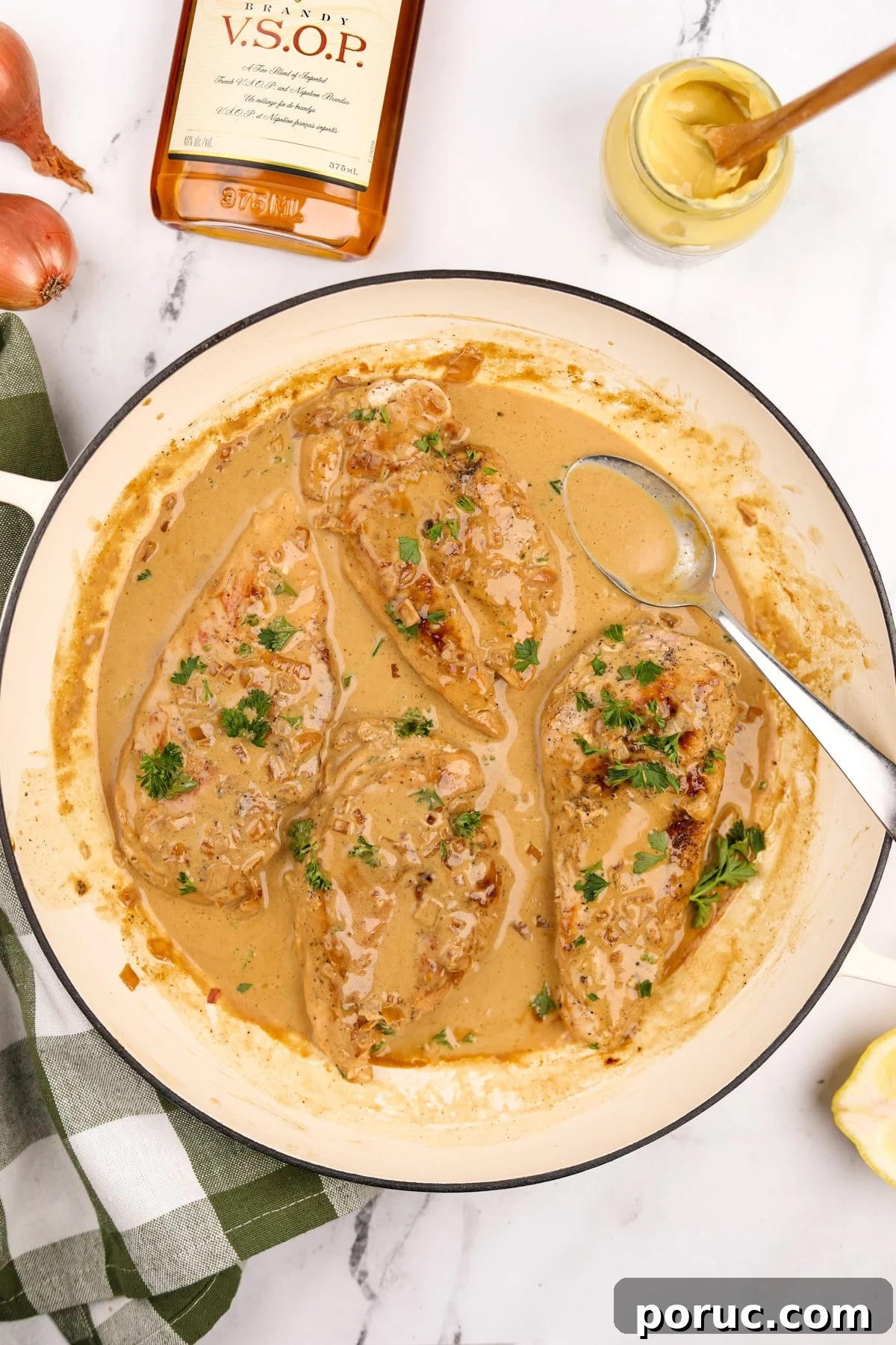 A skillet filled with cooked chicken breasts and a creamy pan sauce.