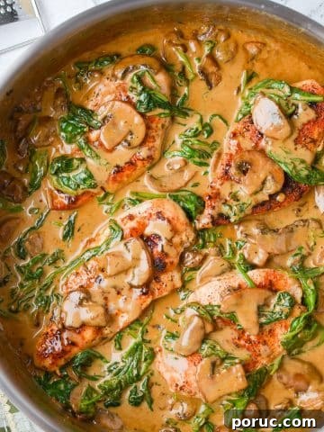 A skillet with chicken covered in a creamy sauce.