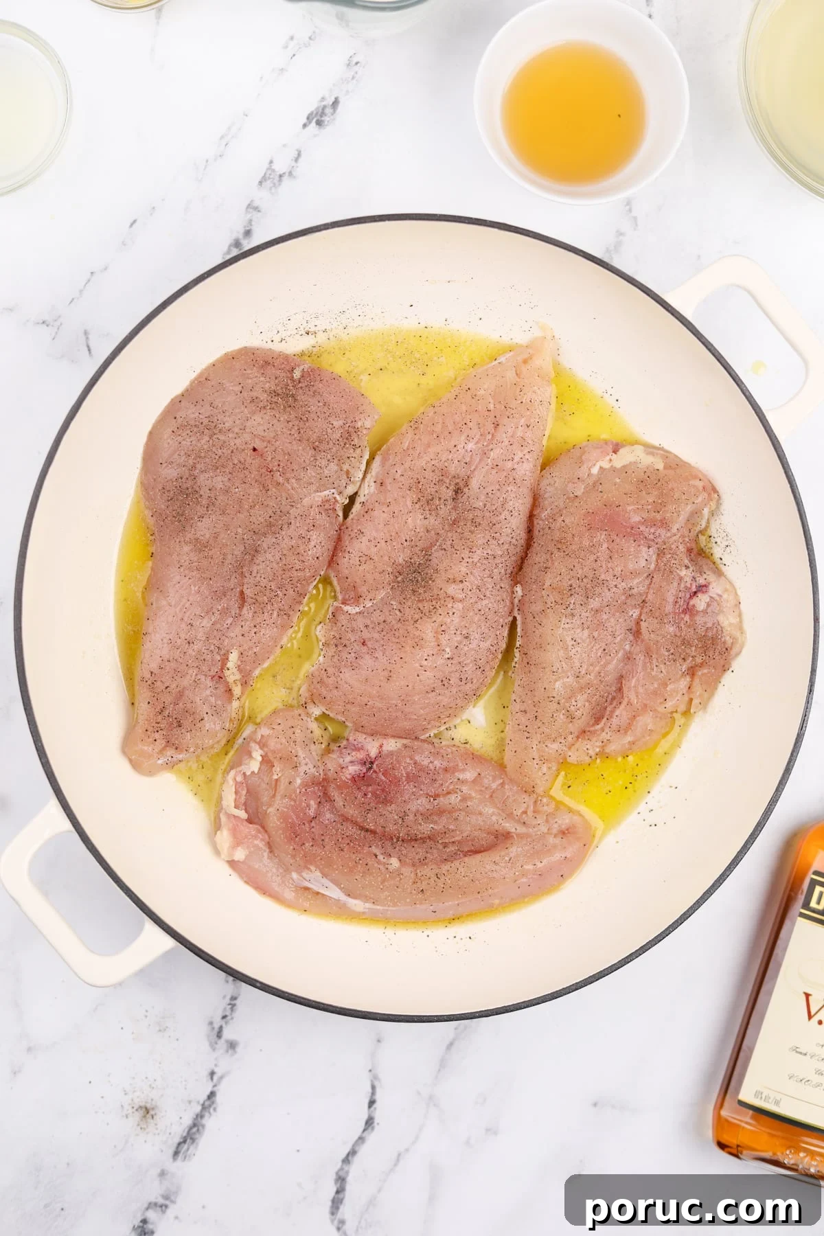 Chicken cutlets added to a skillet with oil and butter.