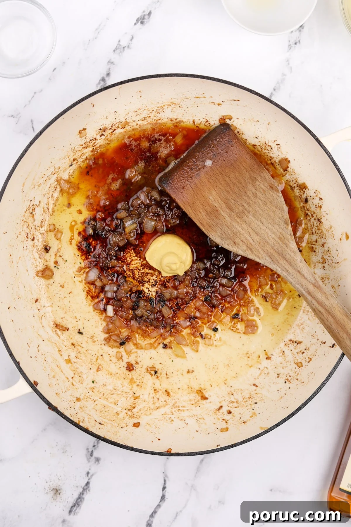 Adding dijon, brandy, and lemon juice to a skillet to make a pan sauce.