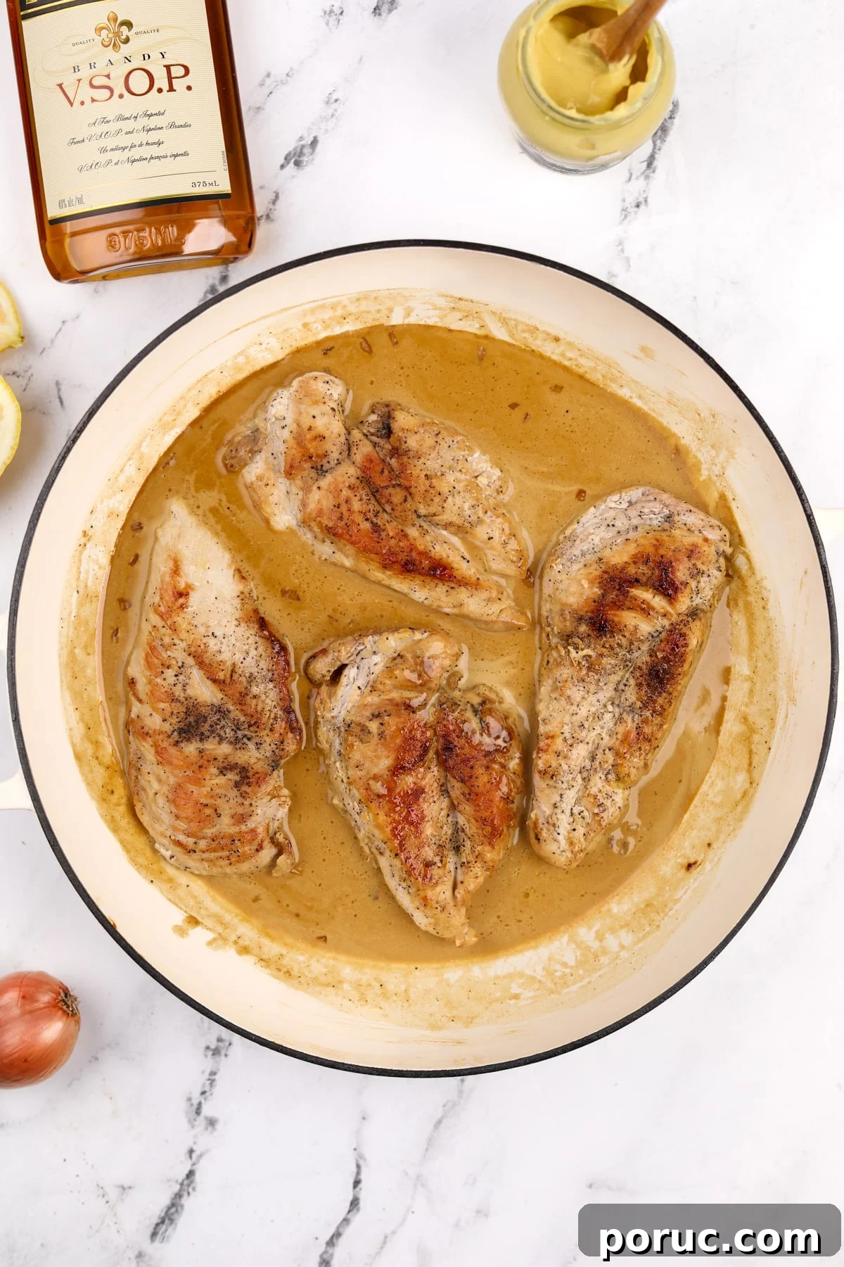 A skillet with a creamy pan sauce and cooked chicken breasts.