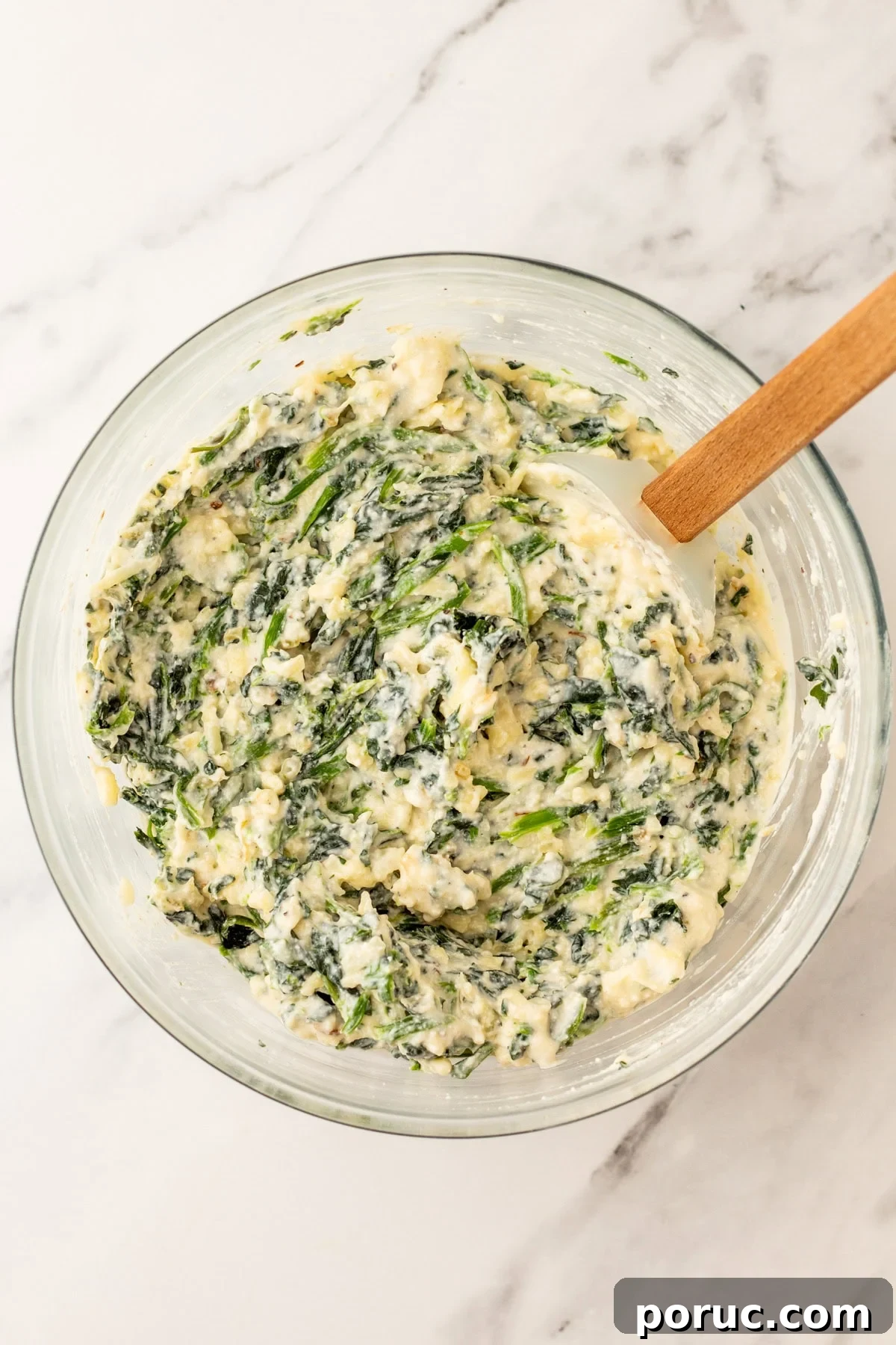 An overhead image of adding spinach and cheese to the mixture.