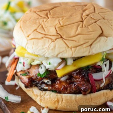 Smoked chicken sandwich on wood board with bowl of coleslaw.