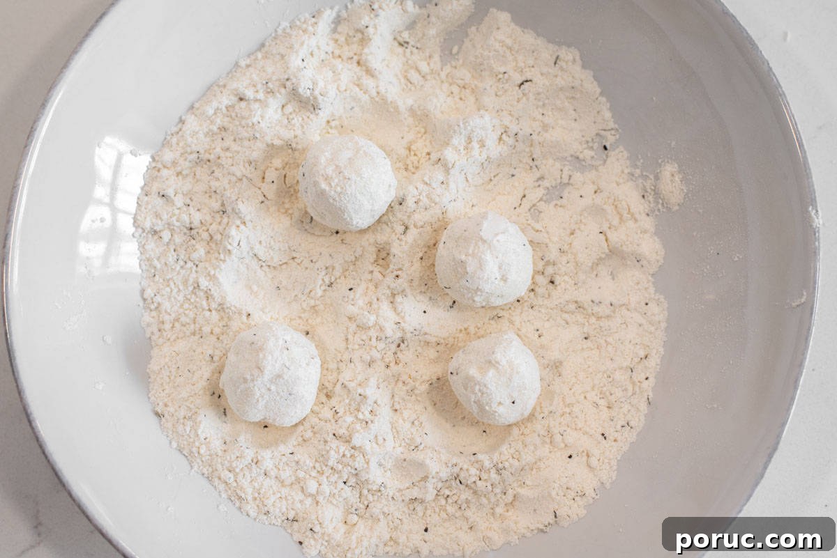 Crispy Fried Goat Cheese Balls with Honey Dip 5 Goat cheese balls mixed in flour mixture in bowl.