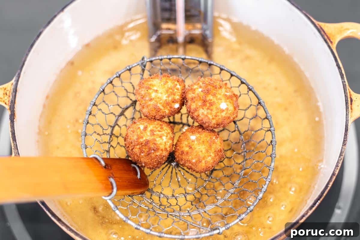 Crispy Fried Goat Cheese Balls with Honey Dip 9 Fried goat cheese balls being pulled out of Dutch oven with oil.