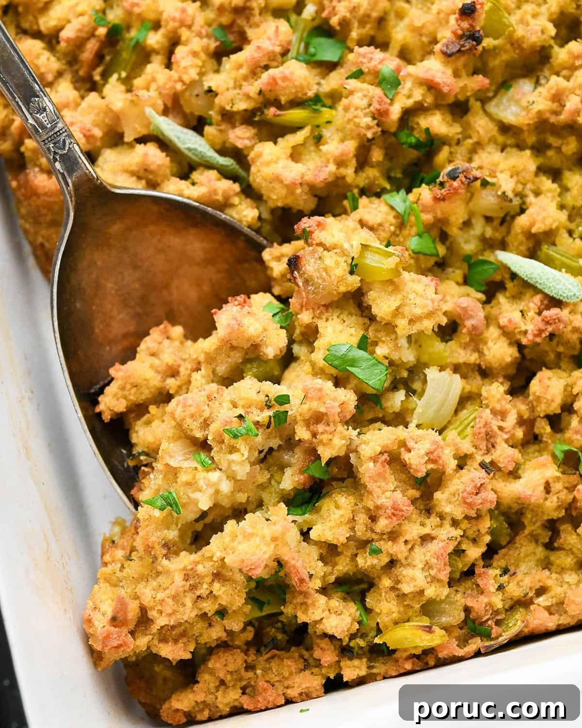 Southern Cornbread Dressing Recipe — Classic Holiday Side Dish 5 up close photo of a spoon taking a scoop of Cornbread stuffing out of a baking dish
