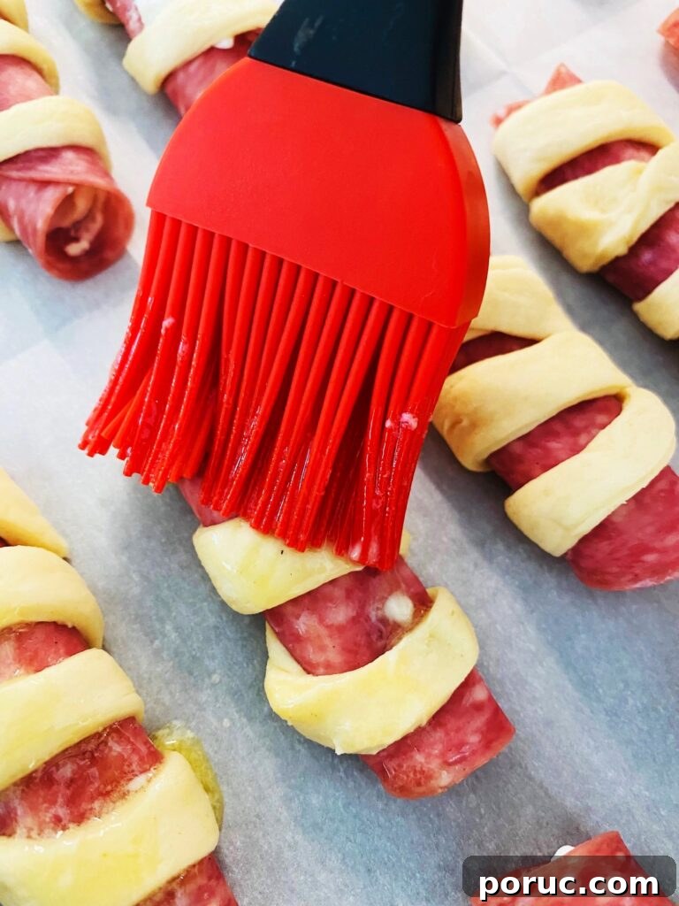 Savory Crescent Salami Roll-Ups for Appetizers and Parties 7 brushing the rolls with melted butter