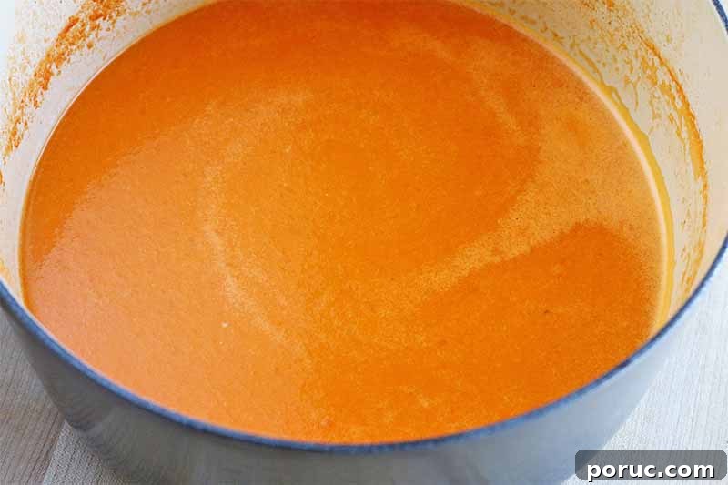 Creamy Tomato Basil Bisque That Elevates Classic Comfort Food 13 Creamy pale orange tomato bisque in a large light blue and white enameled stockpot.