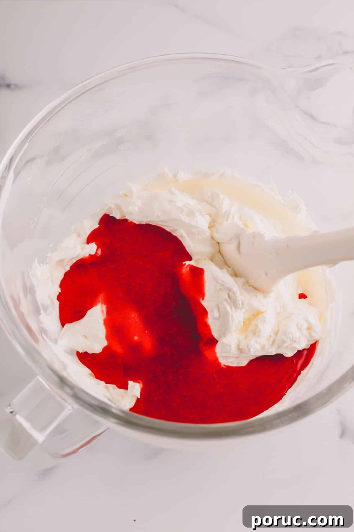 Raspberry sauce being added to buttercream.