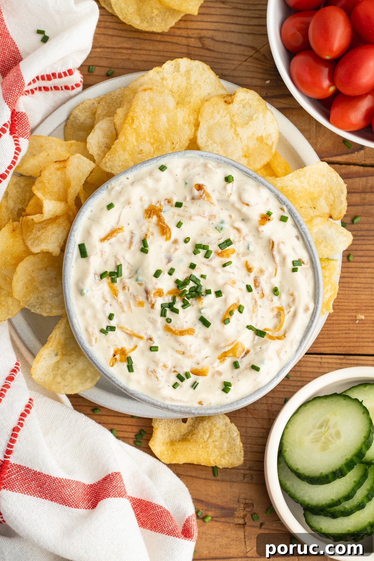 Creamy Caramelized Onion Dip with Greek Yogurt 13 This is a picture of a bowl with the onion dip, chips, tomatoes and cucumber.