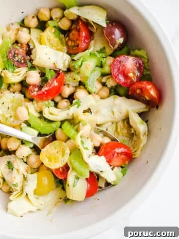 A salad with chickpeas, tomatoes, and avocado in a bowl.