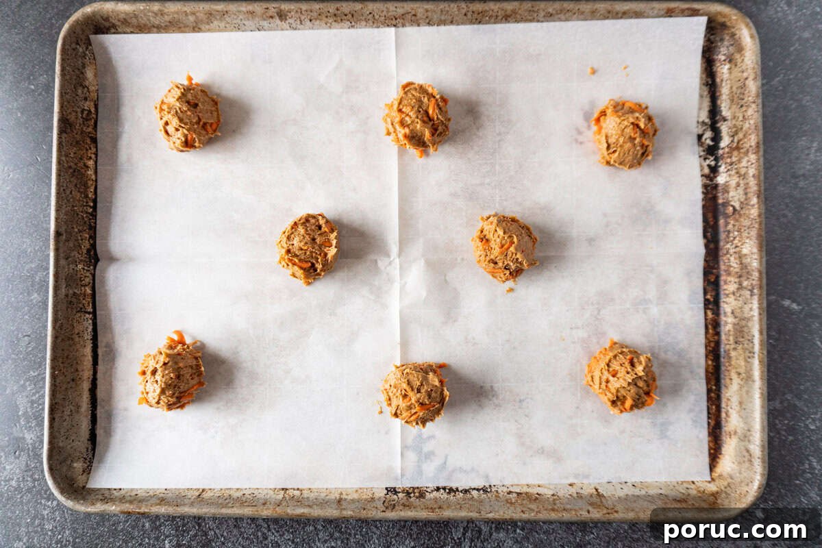 carrot cake cookie dough scooped onto parchment lined baking sheet.