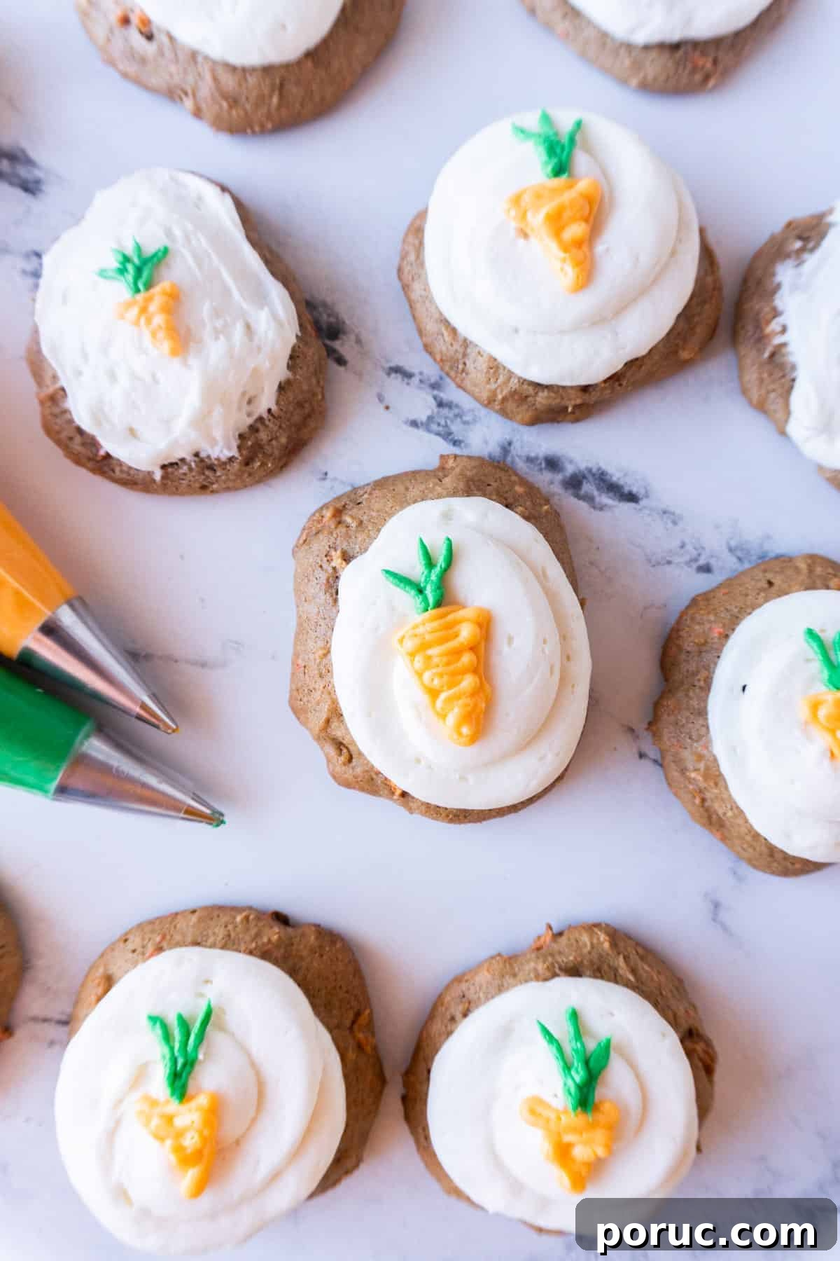 carrot cake cookies with cream cheese frosting and little carrots piped on a marble background.