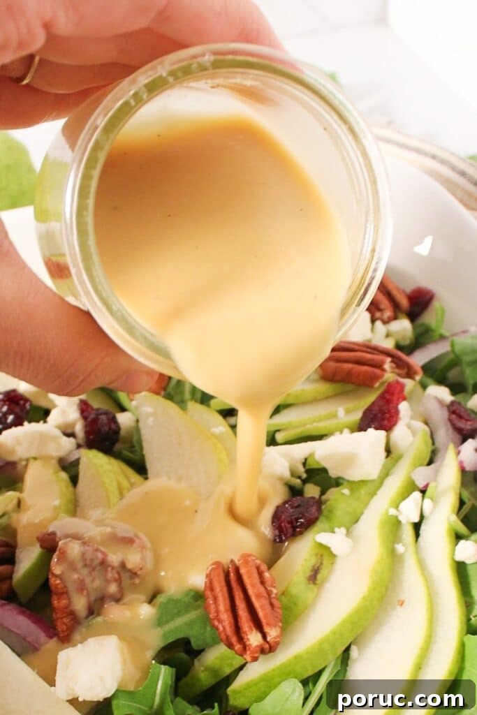 Sherry Shallot Vinaigrette Recipe for Fresh Salads 4 A small glass jar of sherry shallot dressing being poured onto a salad.