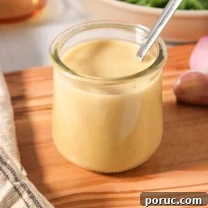 Sherry Shallot Vinaigrette Recipe for Fresh Salads 5 A small glass jar of sherry shallot dressing with a spoon on a wooden board.
