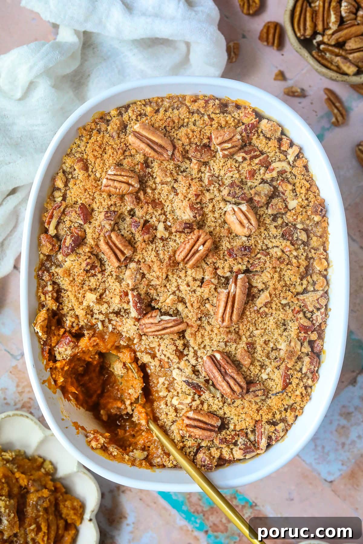 Southern Sweet Potato Casserole with Pecan Crumble Recipe 8 Sweet potato casserole with pecans and crumble topping in a baking dish on a table top.