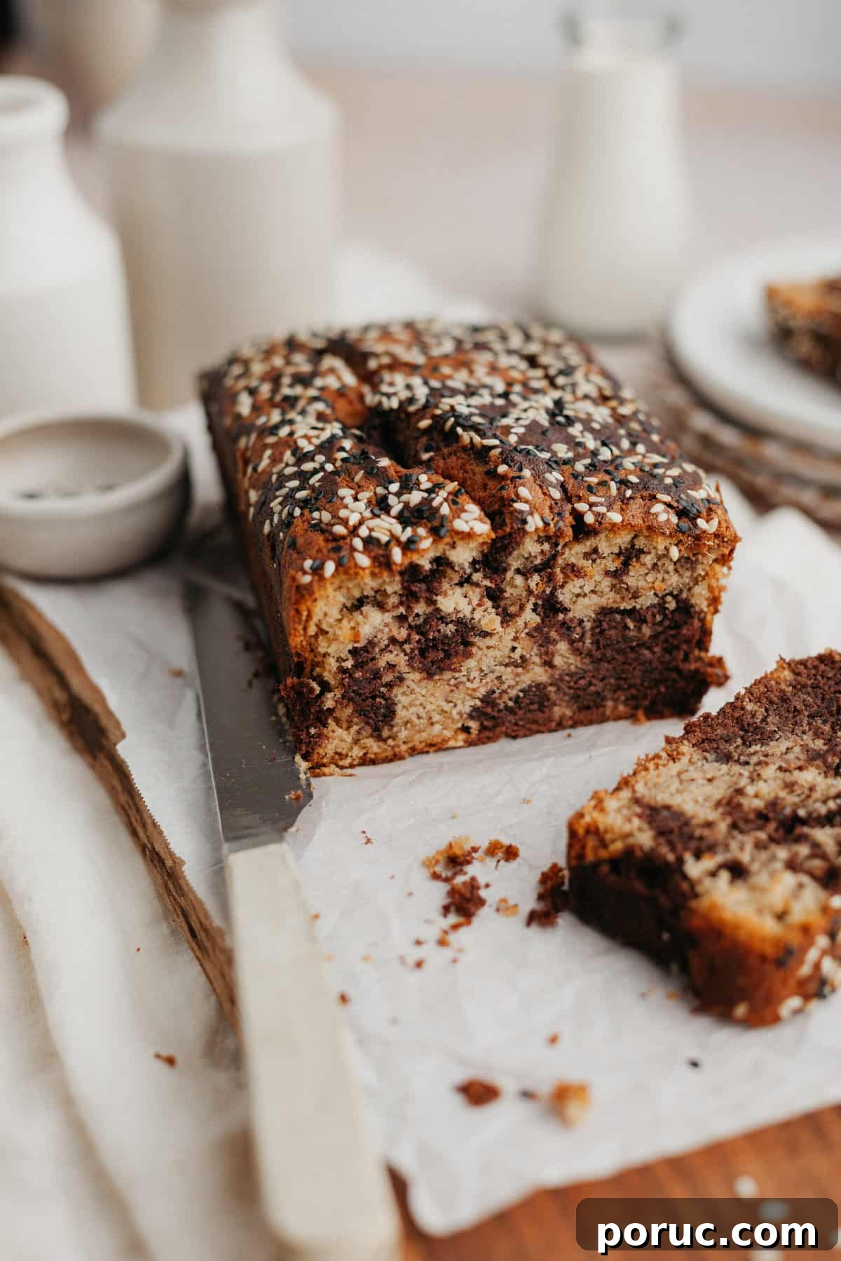 Chocolate Tahini Swirl Banana Bread with Sour Cream Swirl 2 a swirled tahini banana bread on parchment paper, one slice has been cut off.