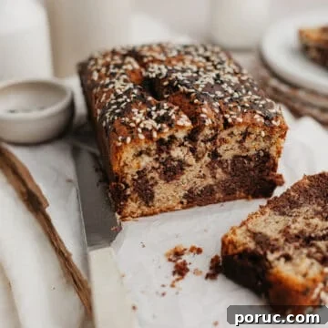 a swirled tahini banana bread on parchment paper, one slice has been cut off.