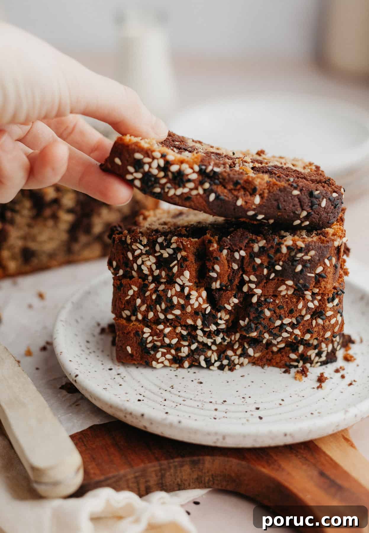 Chocolate Tahini Swirl Banana Bread with Sour Cream Swirl 6 a stack of banana bread slices on a small plate, a hand is lifting one slice off.