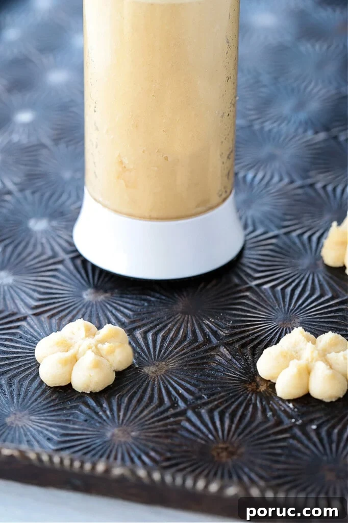 Grandma's Spritz Cookies are a family favorite! Buttery, festive cookies with a hint of sweetness, topped with colorful sprinkles. cookie press on baking sheet