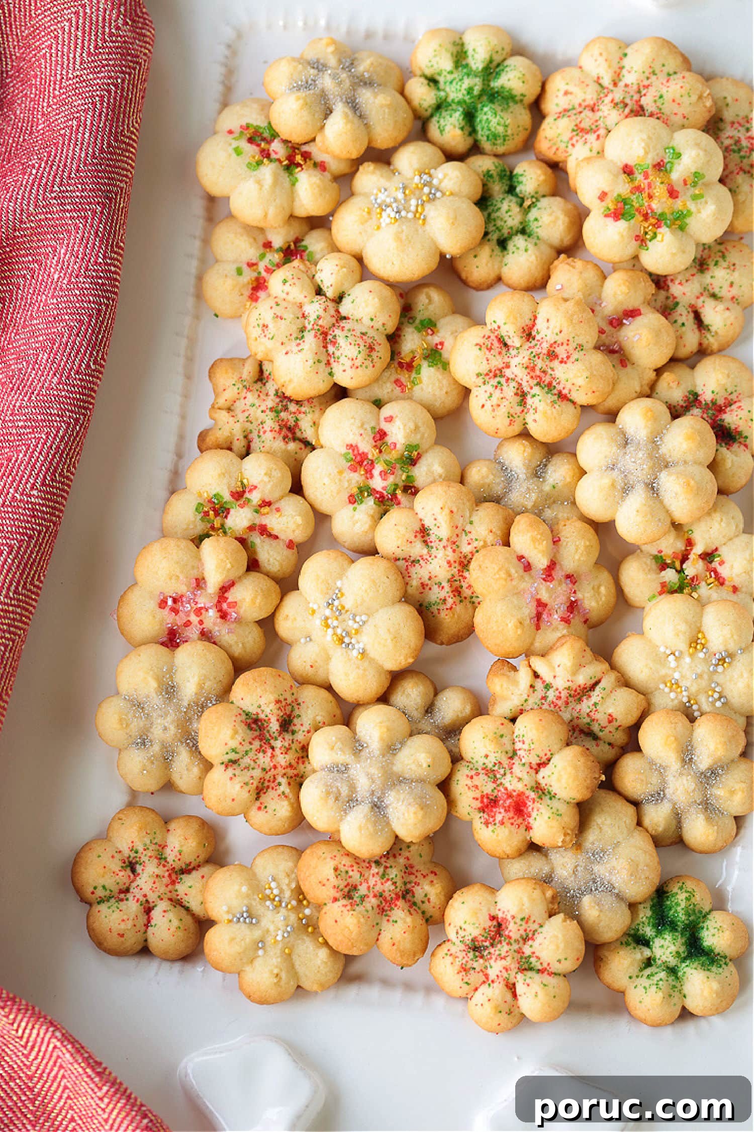 Grandma's Spritz Cookies are a family favorite! Buttery, festive cookies with a hint of sweetness, topped with colorful sprinkles. spritz cookies on white platter with napkin