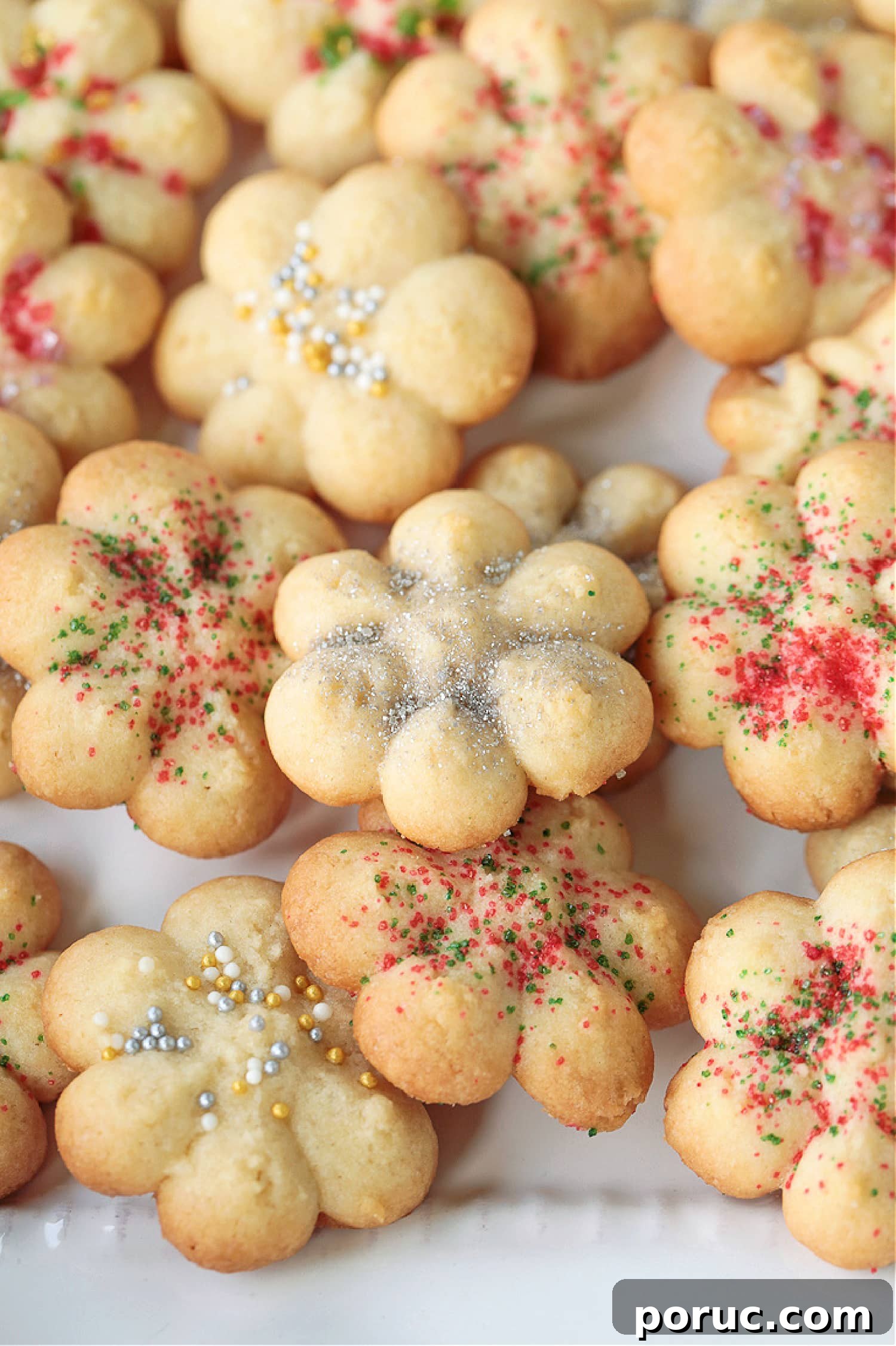 Grandma's Spritz Cookies are a family favorite! Buttery, festive cookies with a hint of sweetness, topped with colorful sprinkles. spritz cookies with silver sprinkles on white plate