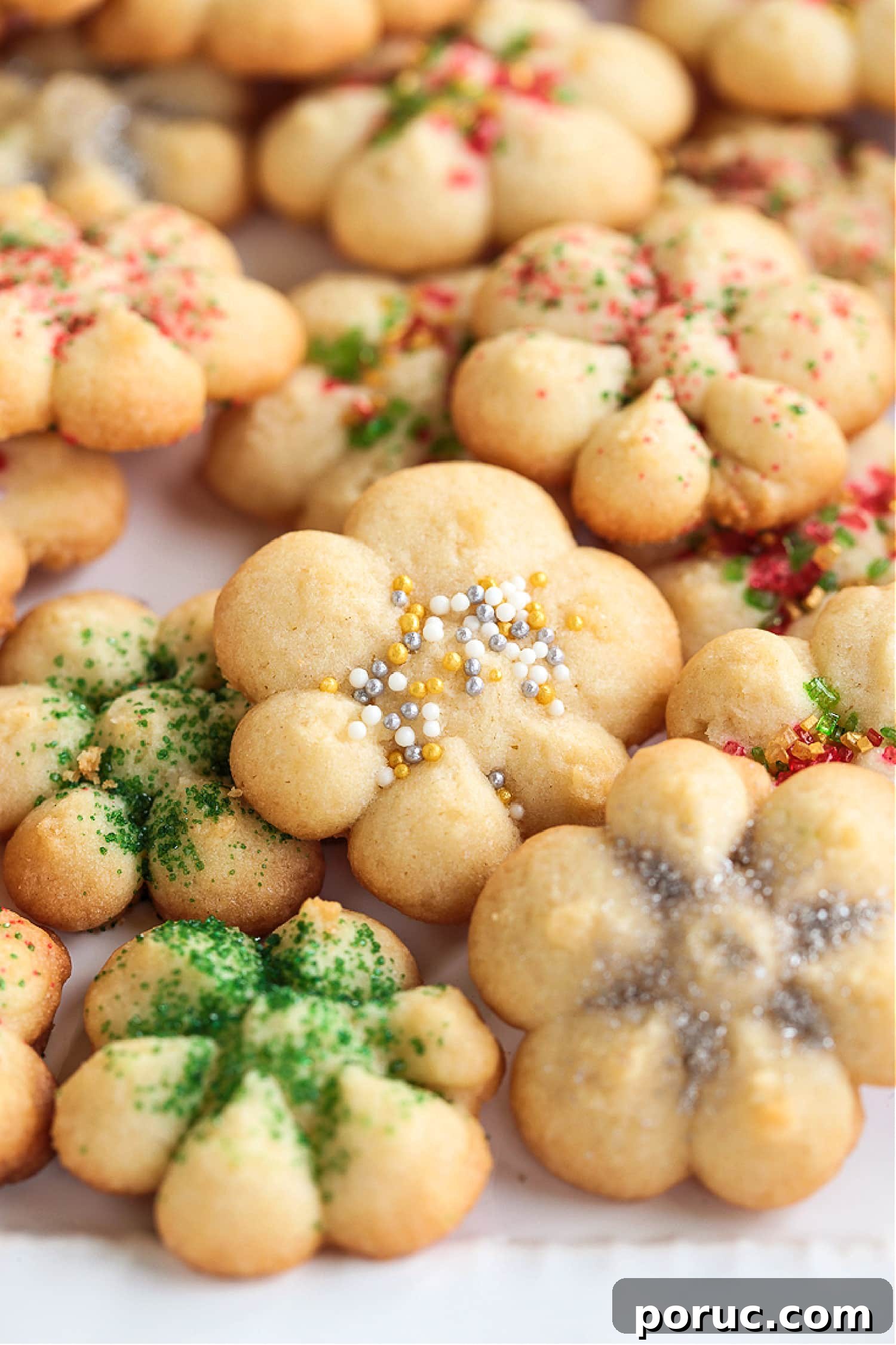 Grandma's Spritz Cookies are a family favorite! Buttery, festive cookies with a hint of sweetness, topped with colorful sprinkles. spritz cookies with sprinkles on plate