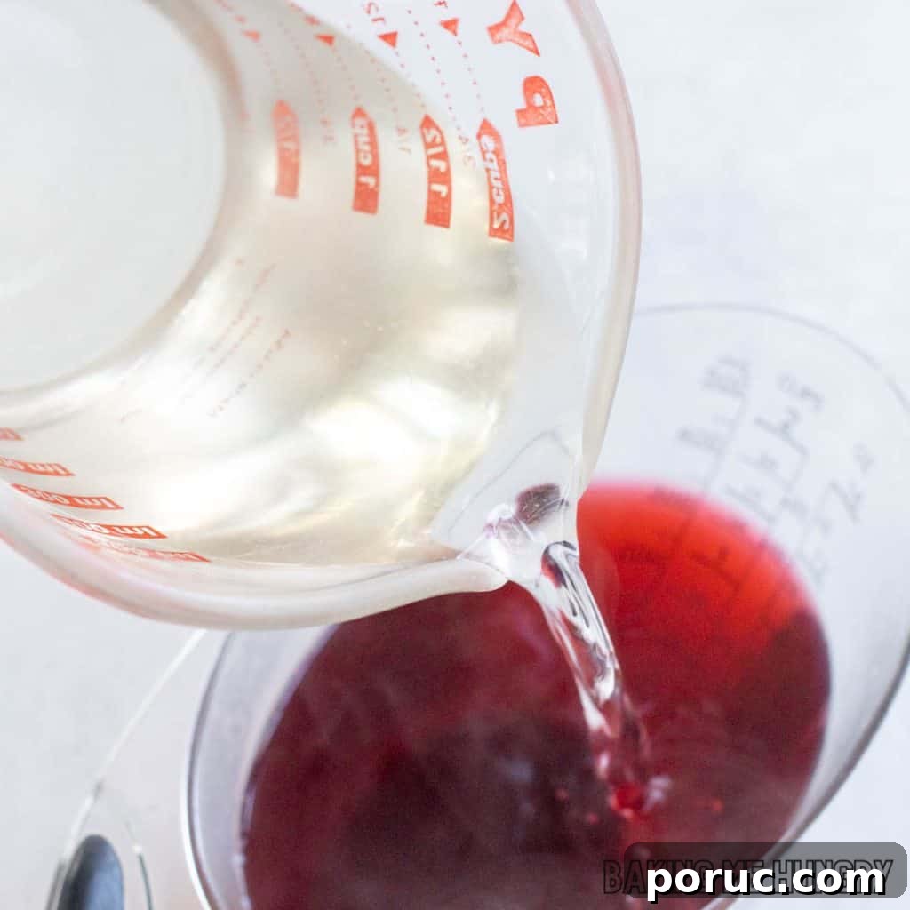 Starbucks-Style Hibiscus Refresher Recipe — How to Make It at Home 6 simple syrup being added to measuring cup
