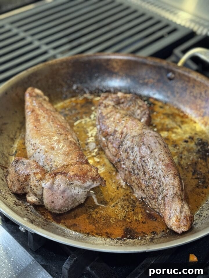 a photo of two pork loins seared in a pan