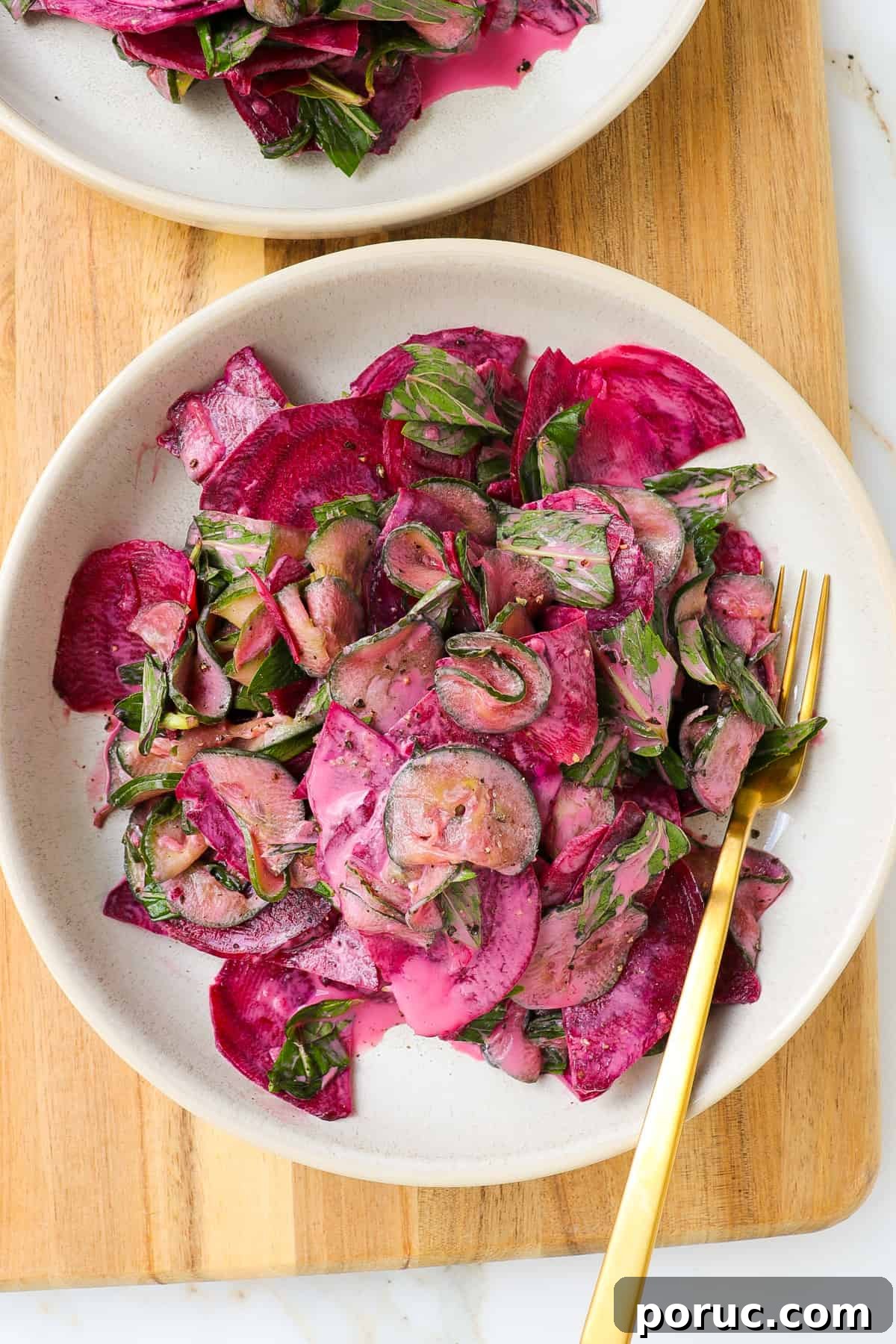 Cucumber beetroot salad in a bowl on a wooden board.