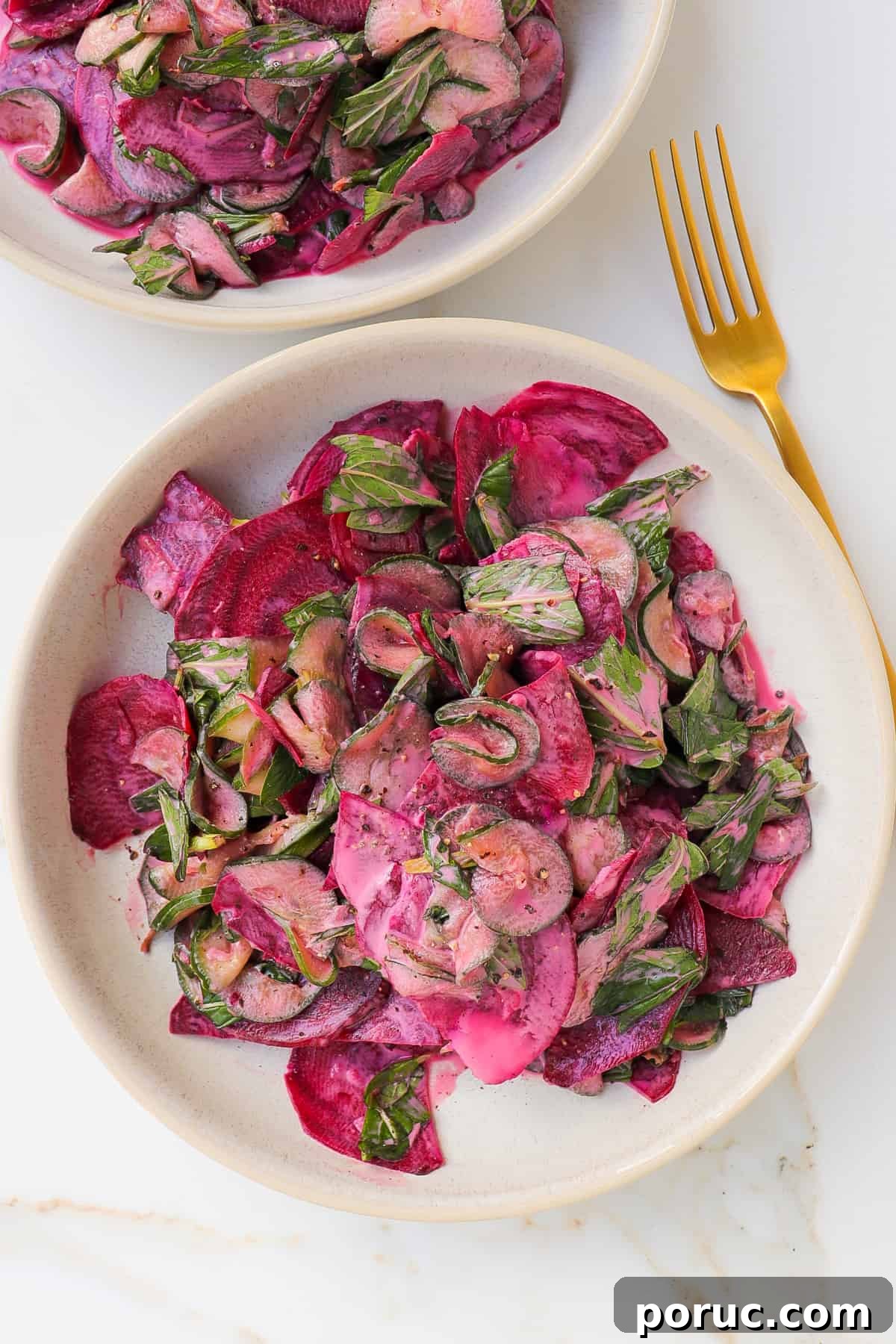 Beetroot salad in a bowl with gold spoon non the side.