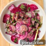 Cucumber beetroot salad in a bowl on a wooden board.