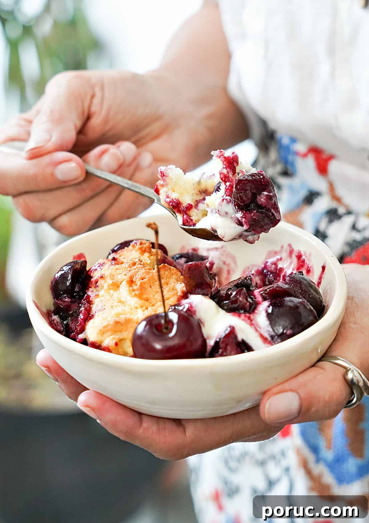 Simple Cherry Cobbler Recipe with Homemade Biscuit Topping 3 Person eating cherry cream cobbler from a white bowl. Colored apron.