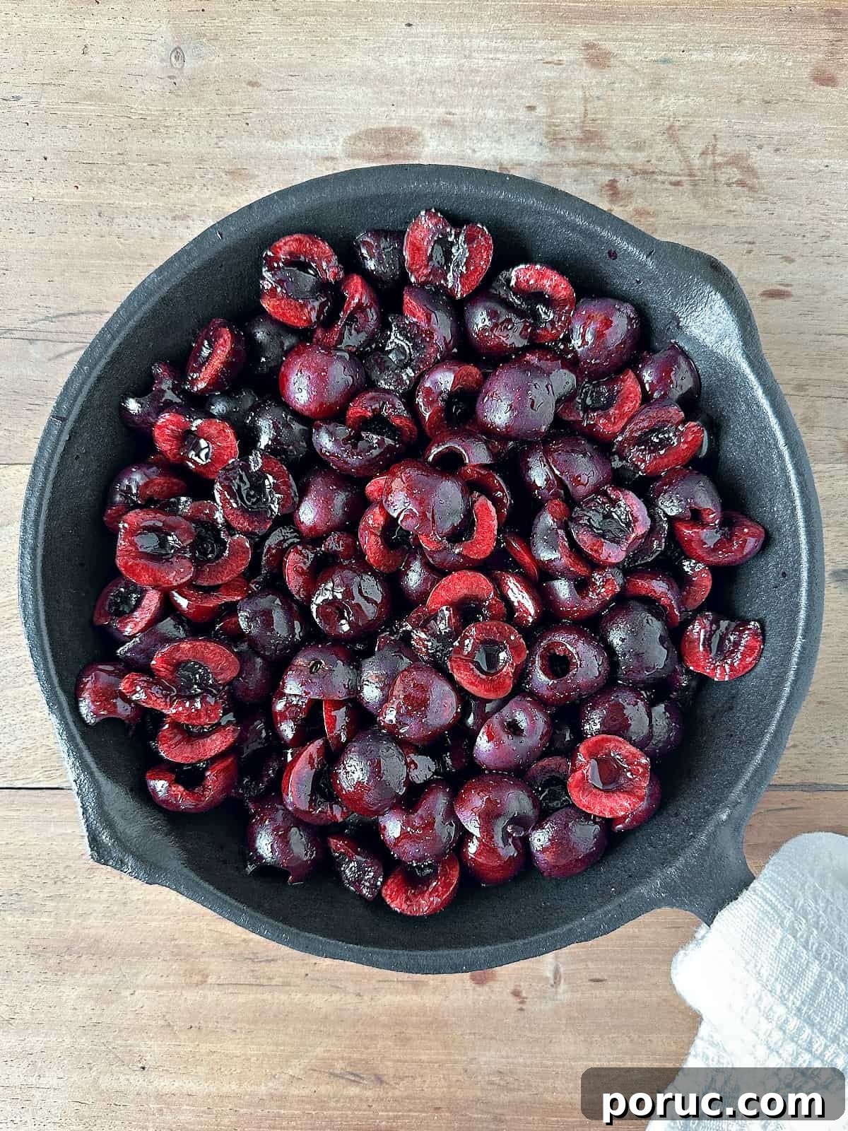 Simple Cherry Cobbler Recipe with Homemade Biscuit Topping 5 Cherry filling in a cast iron skillet on a wooden surface.