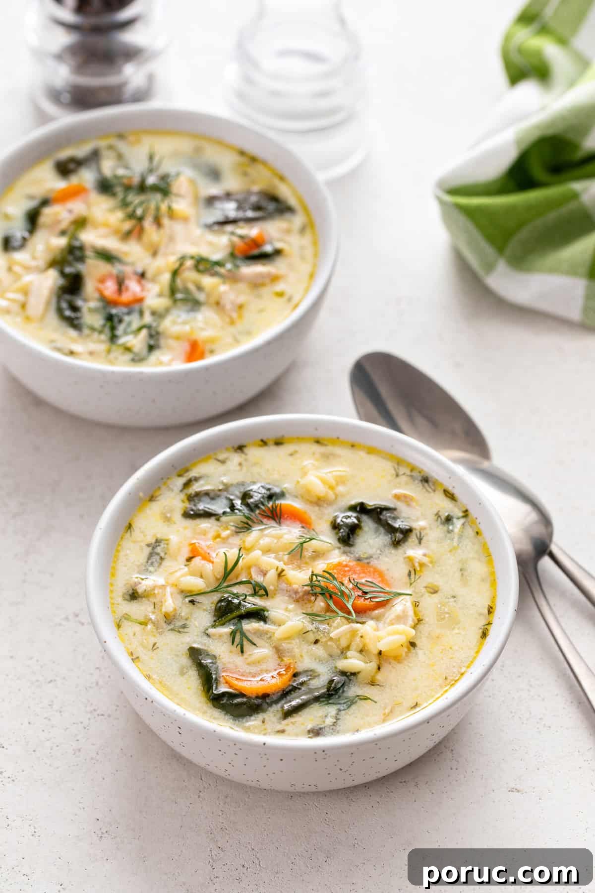 Lemony Chicken and Orzo Soup Recipe for Cozy Meals 2 Two bowls filled with lemon chicken orzo soup next to spoons on a countertop.
