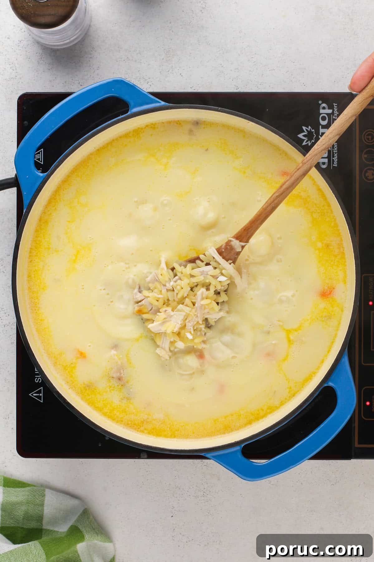 Lemony Chicken and Orzo Soup Recipe for Cozy Meals 9 Spoon showing chicken and cooked orzo in a rich broth in a blue dutch oven.