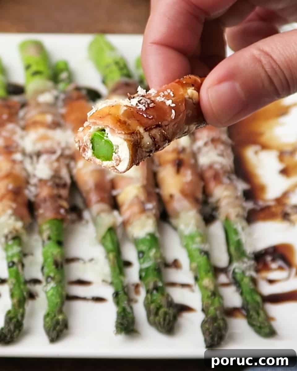 bite shot of Prosciutto Wrapped Asparagus with Cream Cheese topped with parmesan and balsamic glaze