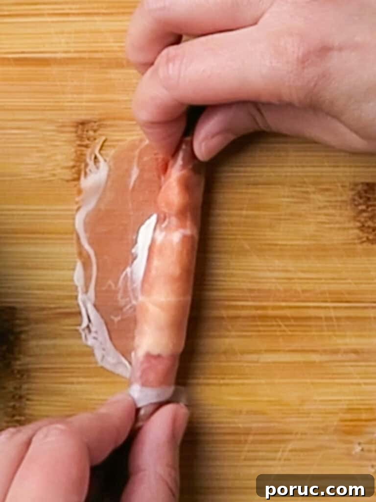 rolling the prosciutto with cream cheese around the asparagus spear