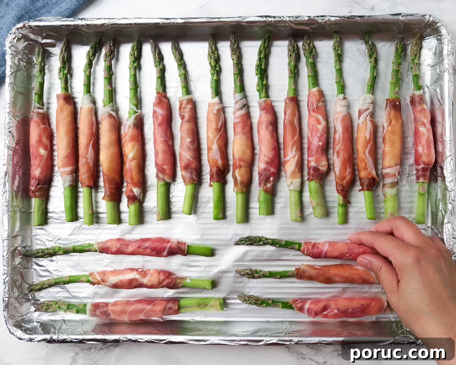 baking tray of prosciutto wrapped asparagus with cream cheese ready to be placed in the oven